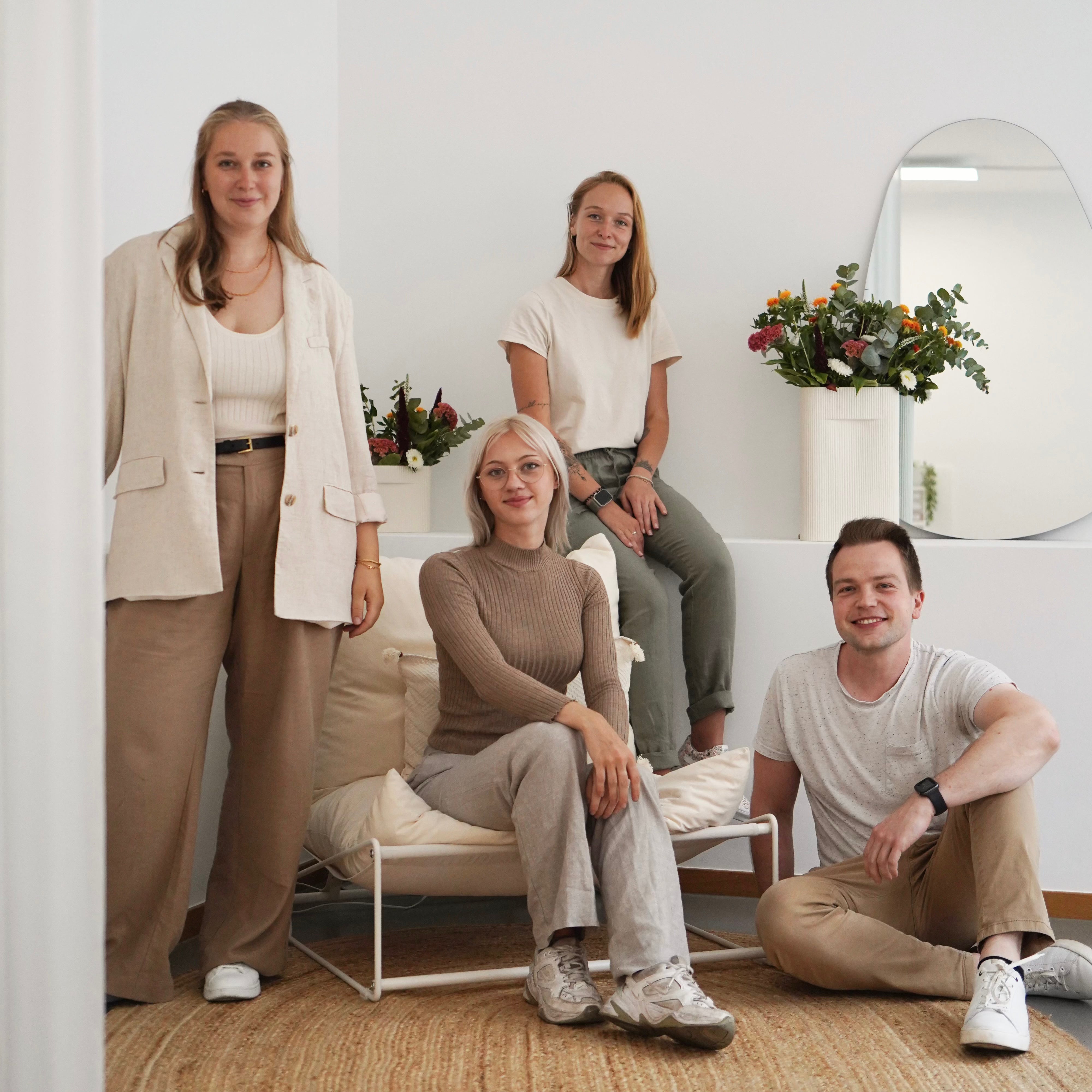 Vier Personen posieren gemeinsam in einem hellen Raum mit Blumen