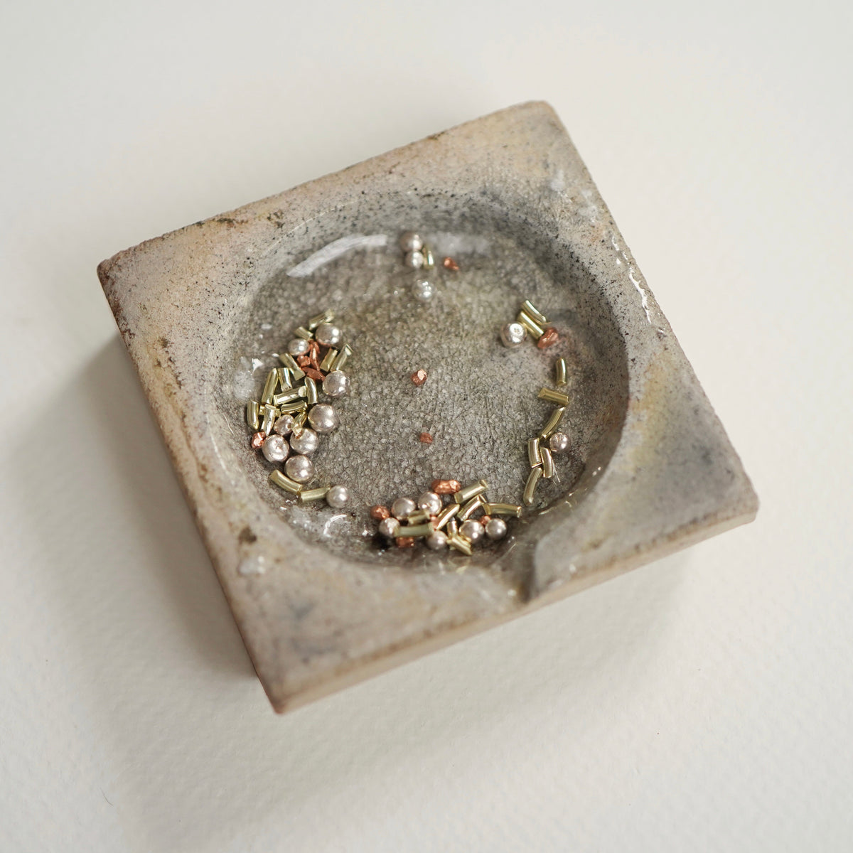 Silber- und goldfarbene Metallstücke in einem Schmelztiegel